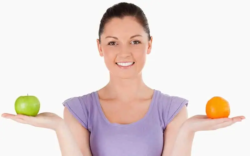 woman holding apples and oranges